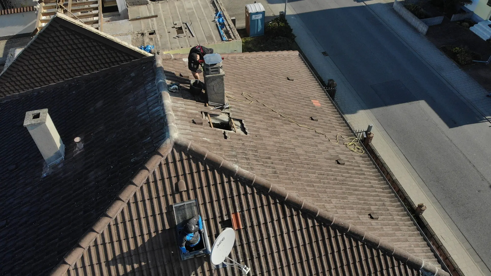 Drohnenaufnahme eines Dachdeckers bei der Reparatur eines Ziegeldachs
